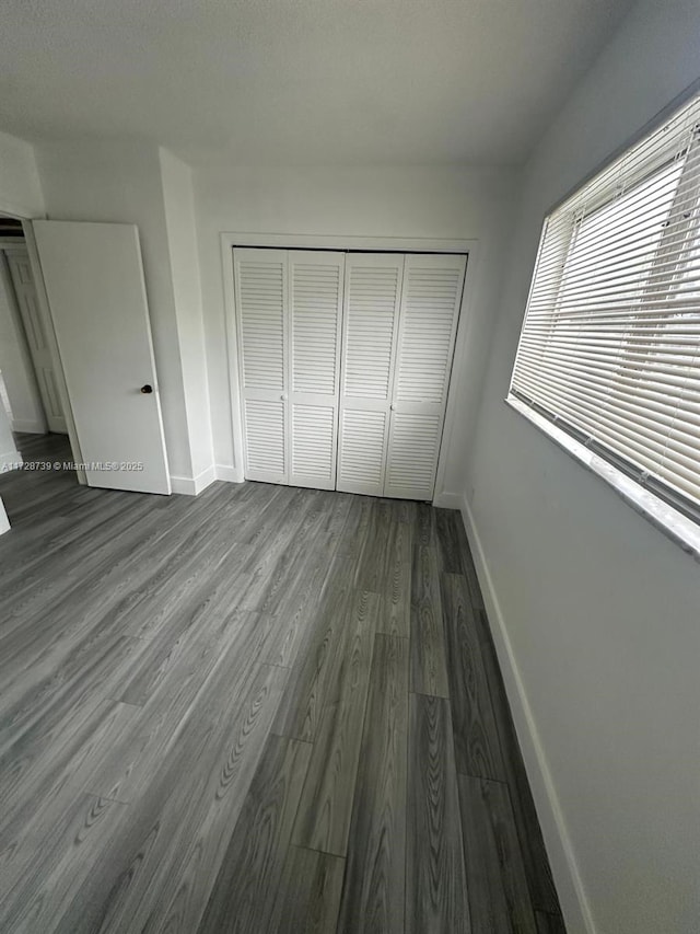 unfurnished bedroom featuring a closet and dark wood-type flooring