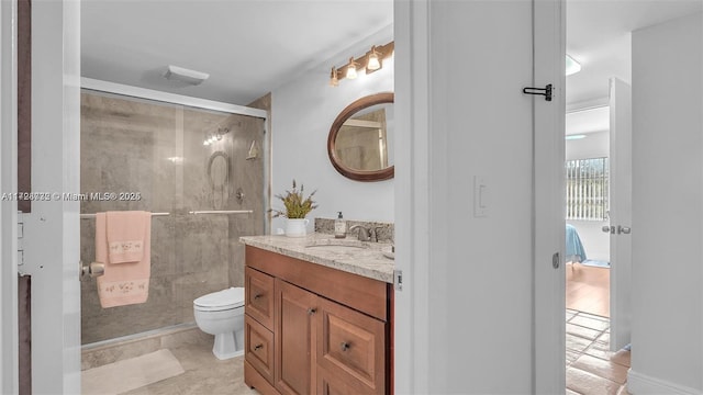 bathroom featuring toilet, tile patterned floors, an enclosed shower, and vanity