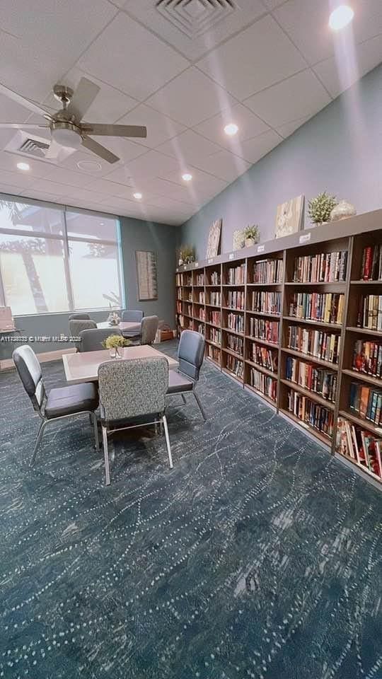 interior space with carpet floors, a paneled ceiling, and ceiling fan