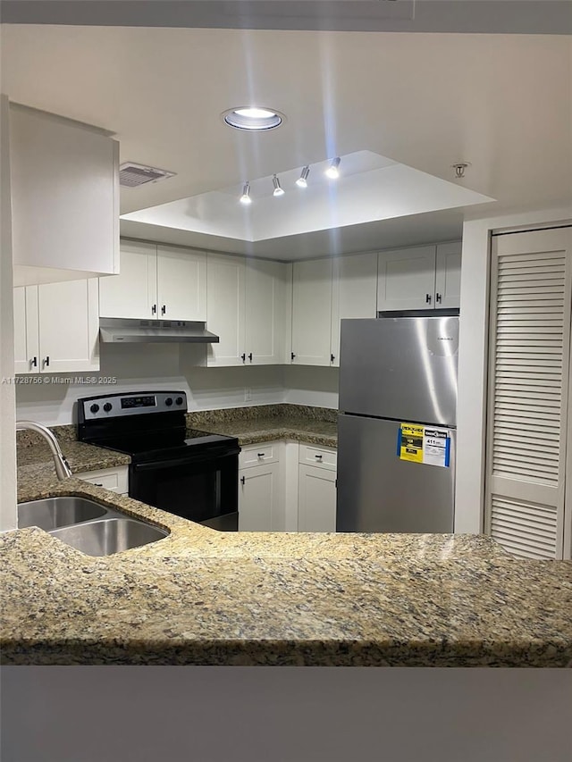 kitchen with dark stone countertops, electric range, sink, stainless steel refrigerator, and white cabinetry