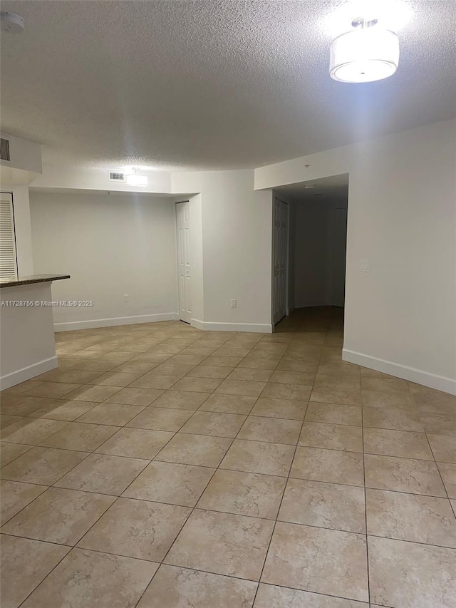 interior space with a textured ceiling and light tile patterned floors