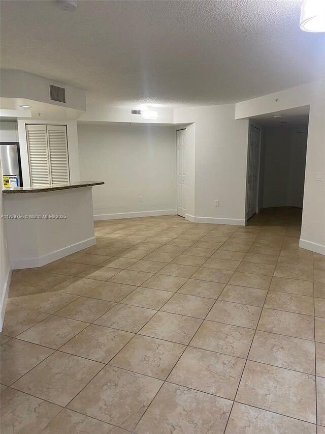 unfurnished room featuring a textured ceiling and light tile patterned floors