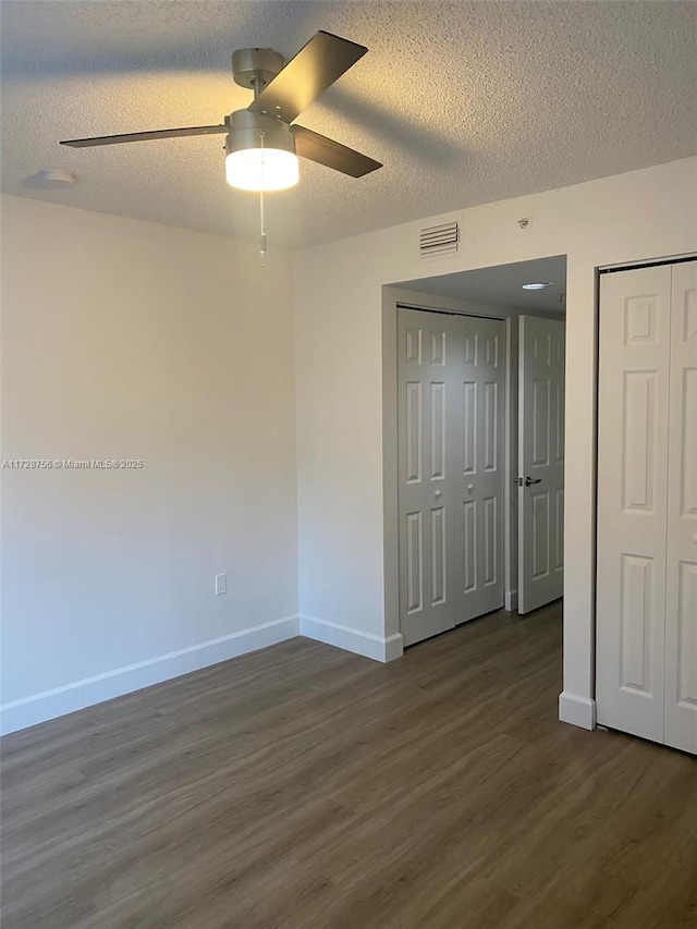 unfurnished bedroom with ceiling fan, dark hardwood / wood-style floors, and a textured ceiling