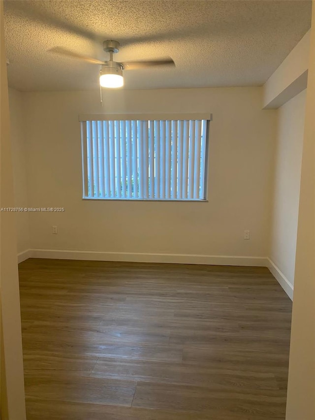 empty room with ceiling fan, dark hardwood / wood-style flooring, and a textured ceiling