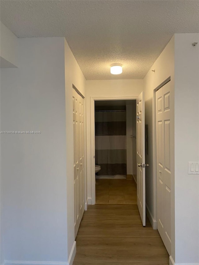 hall featuring a textured ceiling and hardwood / wood-style flooring