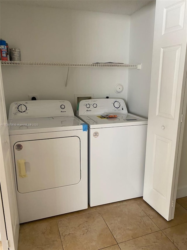 laundry room with washer and dryer and light tile patterned floors