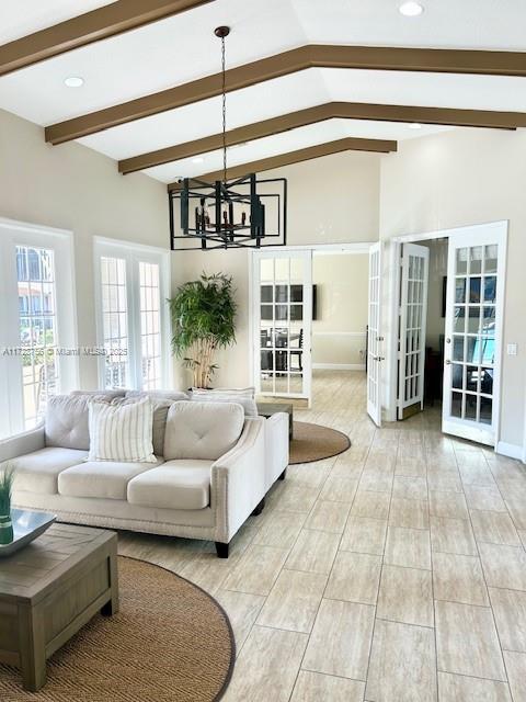 living room with an inviting chandelier, french doors, and vaulted ceiling