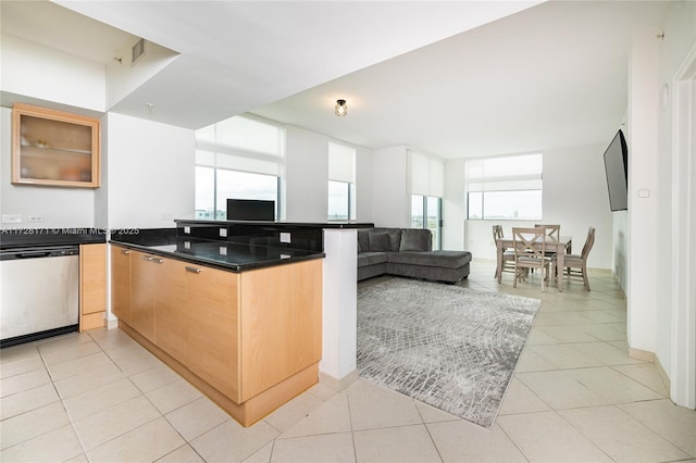 kitchen with light tile patterned floors, kitchen peninsula, dishwasher, and a healthy amount of sunlight