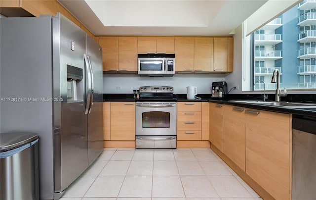 kitchen featuring light tile patterned floors, sink, light brown cabinetry, and appliances with stainless steel finishes