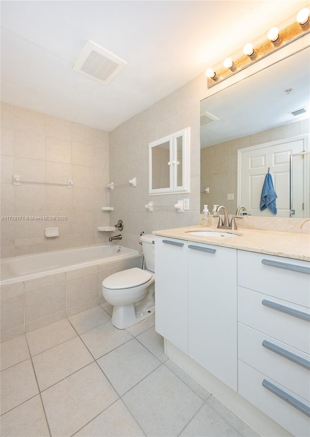 full bathroom with toilet, tiled shower / bath combo, tile walls, tile patterned floors, and vanity