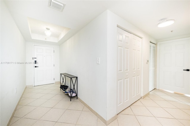 foyer featuring a raised ceiling and light tile patterned flooring