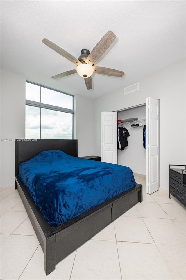 bedroom featuring ceiling fan, tile patterned flooring, and a closet