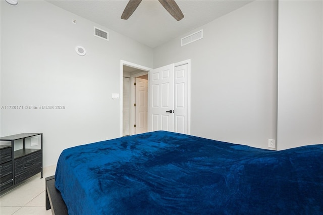 bedroom with a textured ceiling, ceiling fan, and light tile patterned floors