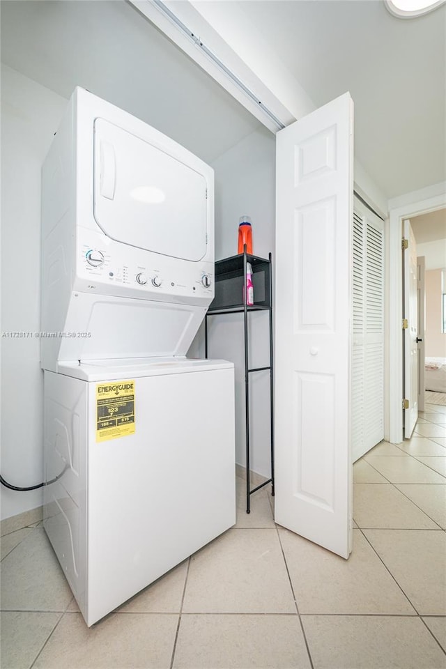 washroom with stacked washer / dryer and light tile patterned flooring