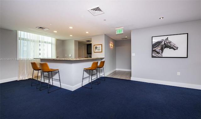 kitchen with a breakfast bar, kitchen peninsula, and carpet flooring