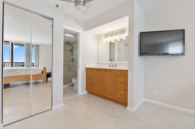 bathroom featuring toilet, ceiling fan, tiled shower, tile patterned floors, and vanity