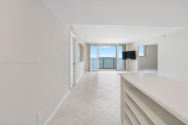 hall with floor to ceiling windows and light tile patterned floors