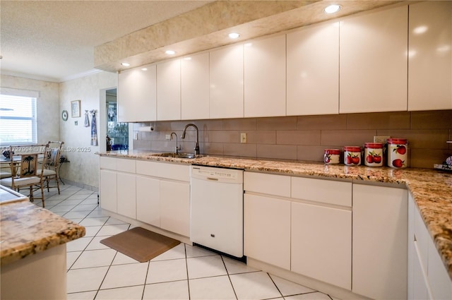 kitchen featuring light tile patterned flooring, sink, white cabinets, white dishwasher, and light stone countertops