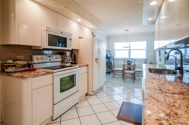 kitchen with sink, white appliances, white cabinetry, light stone countertops, and decorative light fixtures