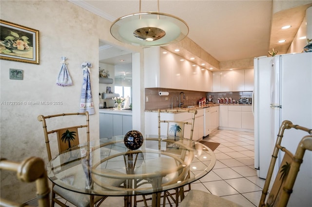 dining area featuring crown molding, sink, and light tile patterned floors