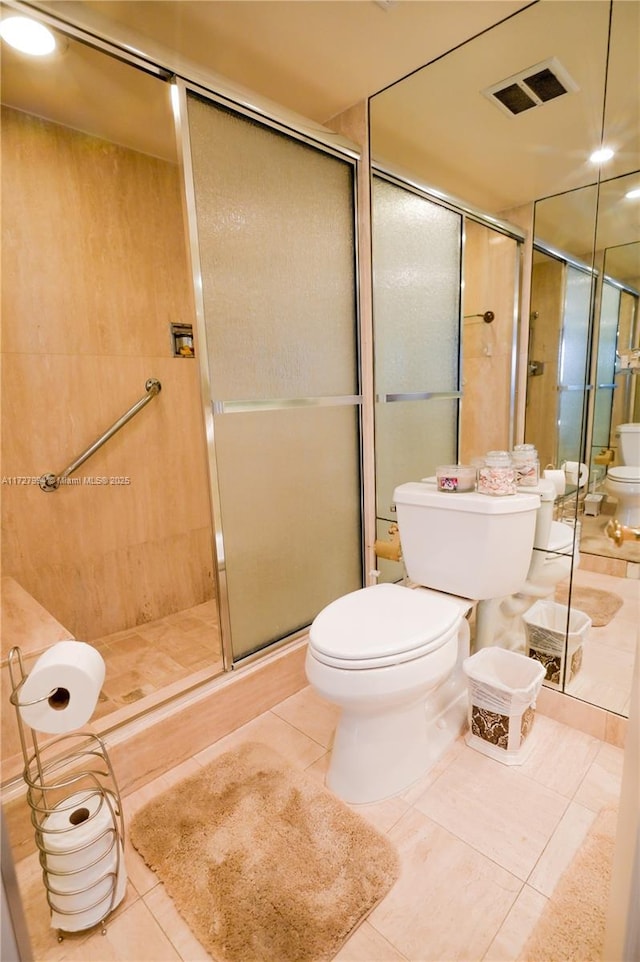 bathroom featuring tile patterned flooring, toilet, and a shower with shower door