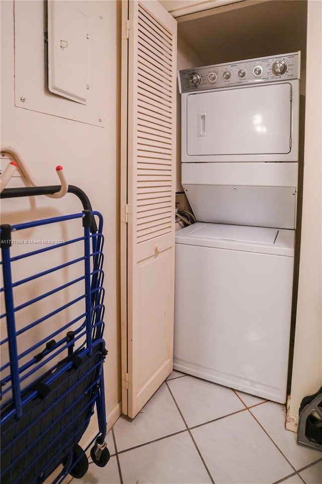 laundry room with stacked washer / dryer and light tile patterned flooring