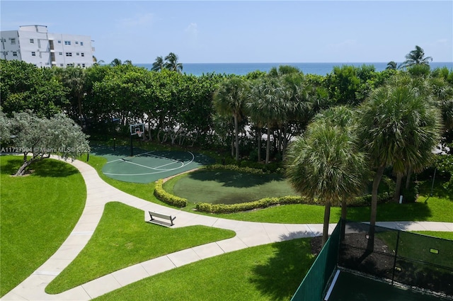 view of community featuring a lawn, basketball hoop, and a water view