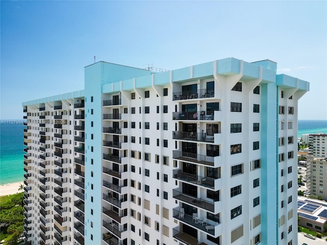 view of building exterior with a beach view and a water view