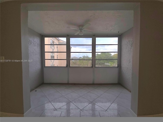 2840 Somerset Dr Unit 318M, Lauderdale Lakes, FL 33311 - empty room with light tile patterned floors, a textured wall, baseboards, and ceiling fan
