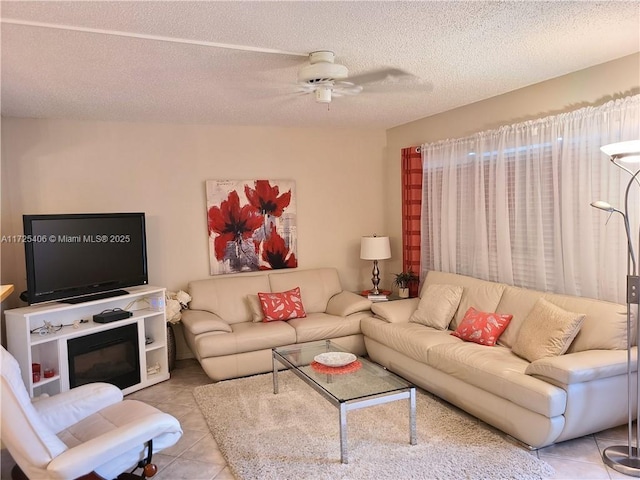 living room with a textured ceiling, ceiling fan, and light tile patterned floors