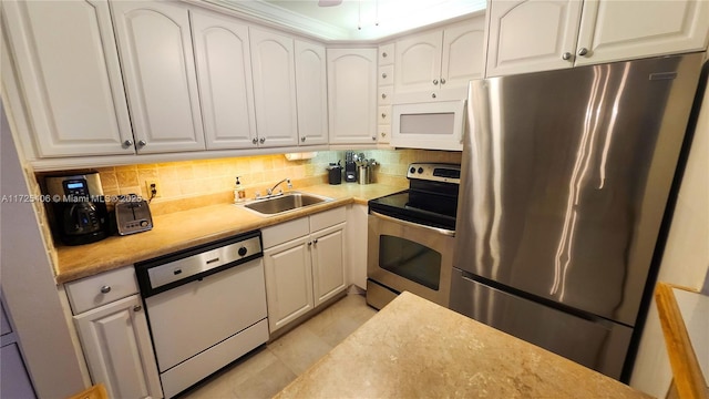 kitchen with appliances with stainless steel finishes, tasteful backsplash, light tile patterned flooring, white cabinets, and sink