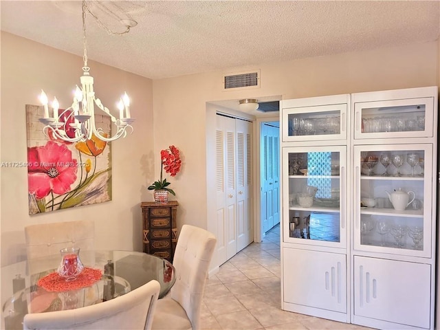 dining room featuring light tile patterned floors, a notable chandelier, and a textured ceiling