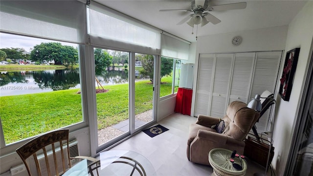 sunroom with ceiling fan and a water view