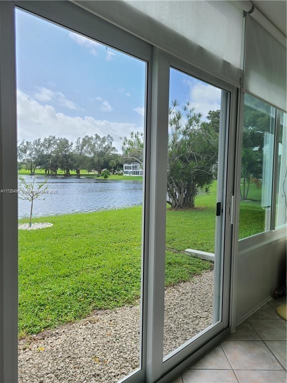 doorway with a healthy amount of sunlight, a water view, and light tile patterned flooring