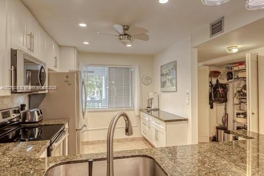 kitchen with ceiling fan, white cabinets, appliances with stainless steel finishes, and sink