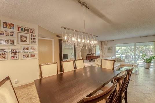 dining area featuring a textured ceiling, light tile patterned flooring, and a notable chandelier