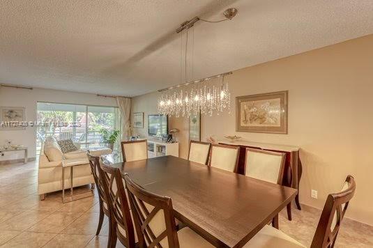 tiled dining room with a textured ceiling and a notable chandelier