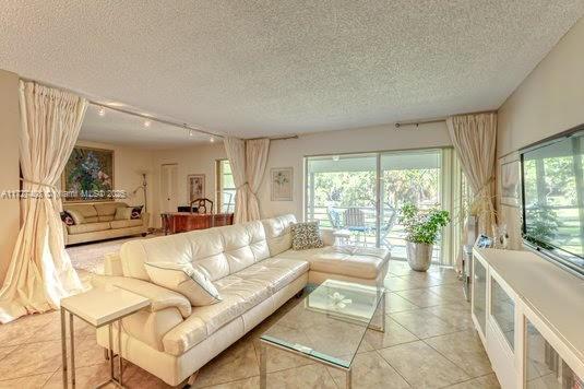 tiled living room featuring a textured ceiling and rail lighting