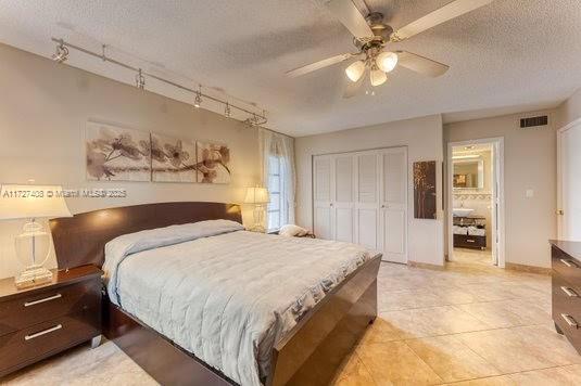 bedroom with a textured ceiling, ceiling fan, track lighting, and a closet