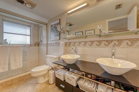 bathroom with tile walls, toilet, vanity, and tile patterned flooring