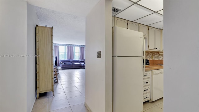 kitchen featuring a textured ceiling, light tile patterned floors, tasteful backsplash, and white appliances