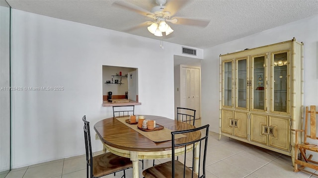 dining area featuring ceiling fan, light tile patterned floors, and a textured ceiling