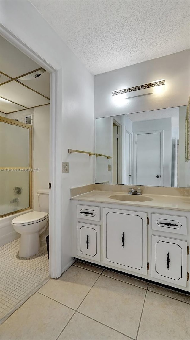 full bathroom with toilet, vanity, tile patterned floors, combined bath / shower with glass door, and a textured ceiling