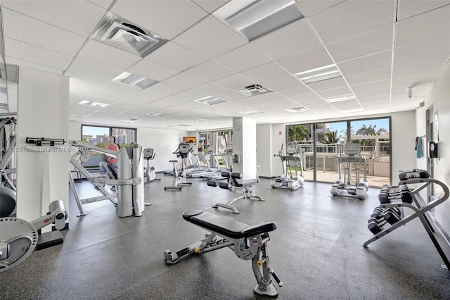 gym with a drop ceiling and a wall of windows