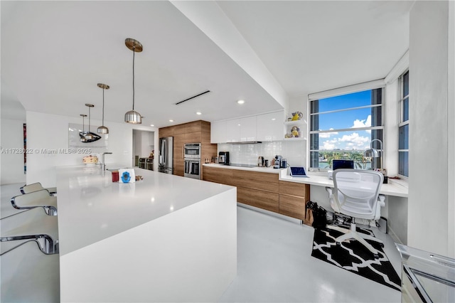 kitchen featuring white cabinetry, pendant lighting, stainless steel appliances, and backsplash