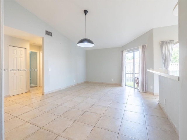 spare room featuring light tile patterned flooring and lofted ceiling