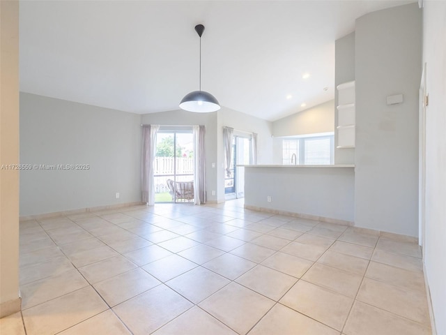 empty room with vaulted ceiling and light tile patterned flooring