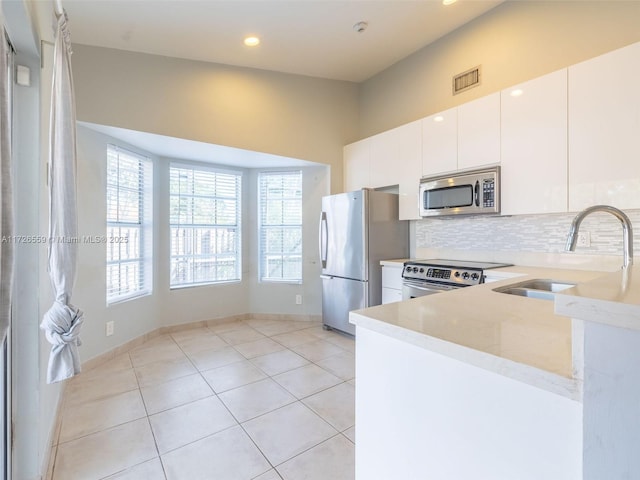 kitchen with sink, white cabinetry, stainless steel appliances, light stone counters, and decorative backsplash