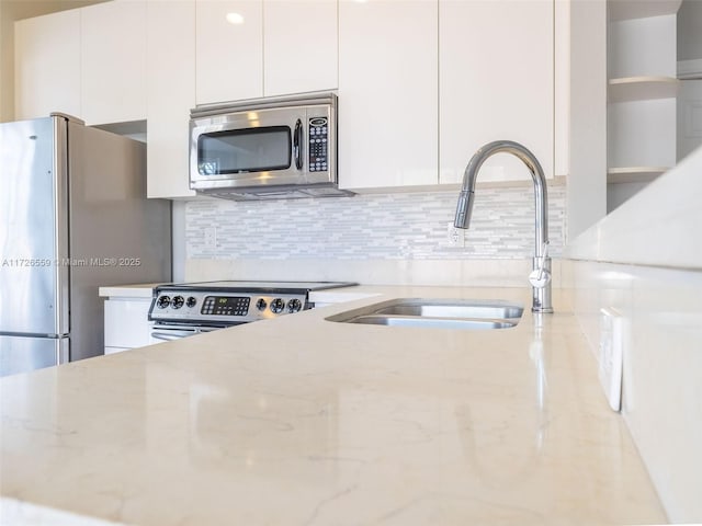 kitchen featuring stainless steel appliances, sink, white cabinets, and light stone counters