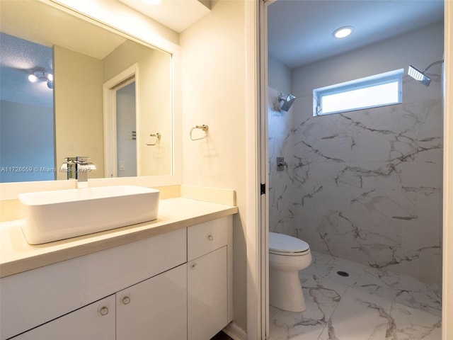 bathroom with tiled shower, vanity, and toilet